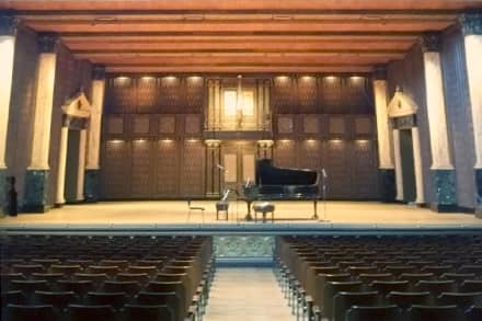 Grand piano on stage with theatre seating for a music recital